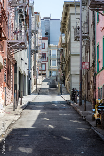 Fototapeta Naklejka Na Ścianę i Meble -  Narrow steep street in San Francisco with clean sidewalks and old fire escapes