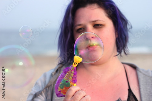 Beautiful woman shooting bubble gun on the beach 