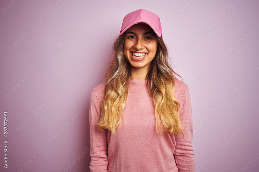 Young beautiful woman wearing cap over pink isolated background with a happy and cool smile on face. Lucky person. Young beautiful woman wearing cap over pink isolated background with a happy and cool smile on face. Lucky person.