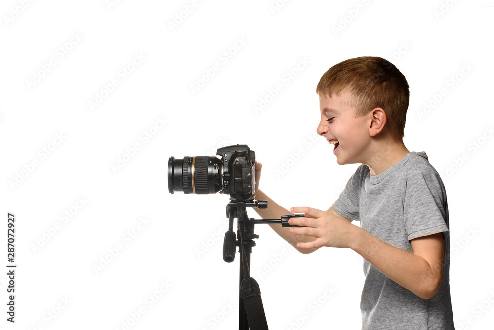 Laughing schoolboy shoots video on DSLR camera. Side view. White background, isolate Laughing schoolboy shoots video on DSLR camera. Side view. White background, isolate