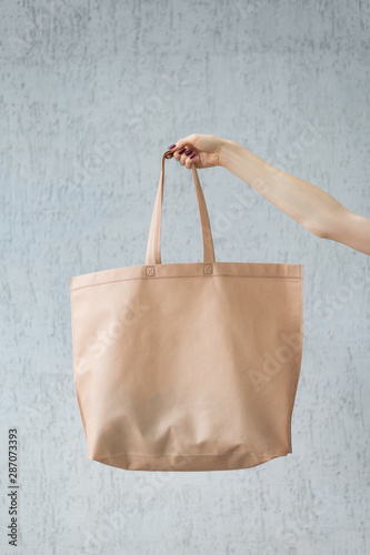 Large eco shopping bag in the hand of a young woman. Copy space. White background