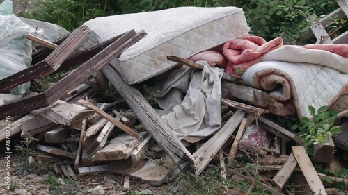 Garbage dumped in the yard near the house: boards, mattress, comforter