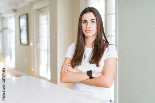 Beautiful young woman wearing casual white t-shirt skeptic and nervous, disapproving expression on face with crossed arms. Negative person.