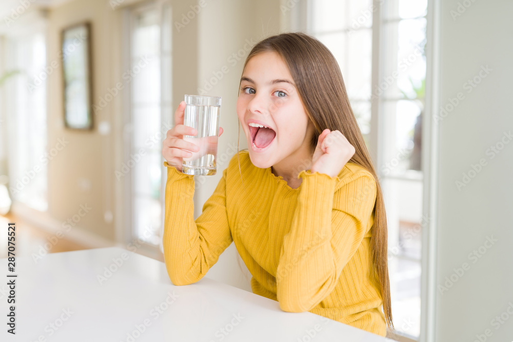 Beautiful young girl kid drinking a fresh glass of water screaming proud and celebrating victory and success very excited, cheering emotion Beautiful young girl kid drinking a fresh glass of water screaming proud and celebrating victory and success very excited, cheering emotion