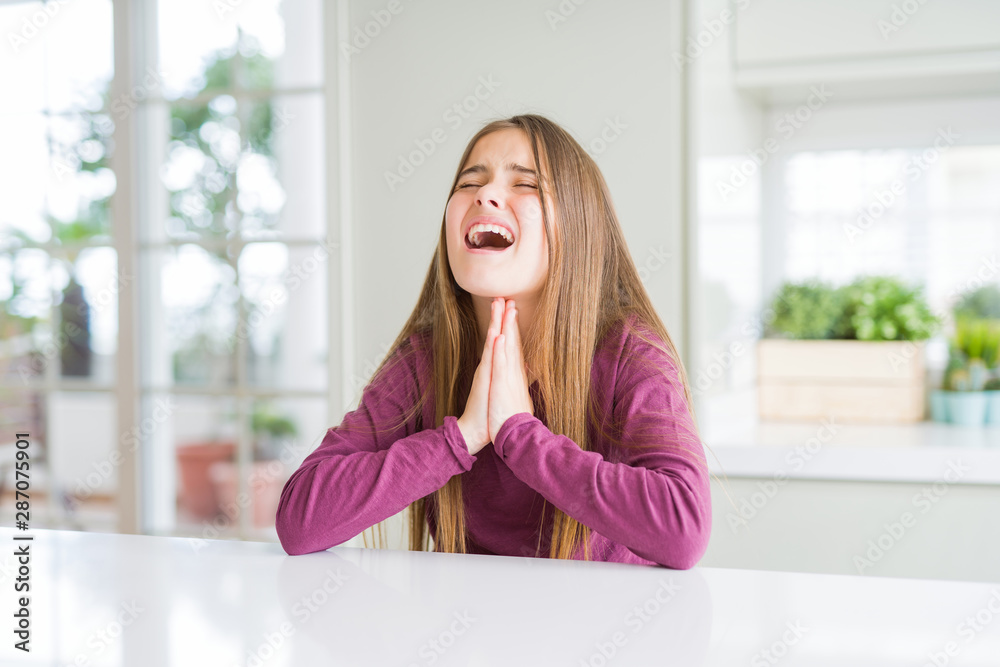 Beautiful young girl kid on white table begging and praying with hands together with hope expression on face very emotional and worried. Asking for forgiveness. Religion concept. Beautiful young girl kid on white table begging and praying with hands together with hope expression on face very emotional and worried. Asking for forgiveness. Religion concept.