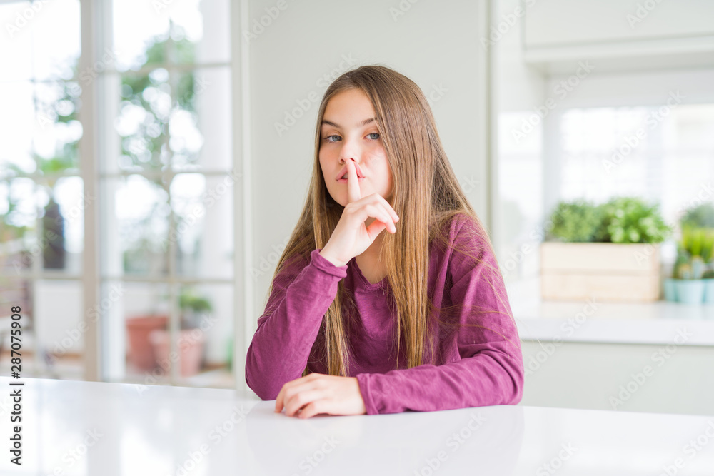 Beautiful young girl kid on white table asking to be quiet with finger on lips. Silence and secret concept. Beautiful young girl kid on white table asking to be quiet with finger on lips. Silence and secret concept.