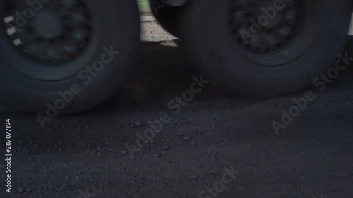 Cars drive along an old asphalt road with potholes