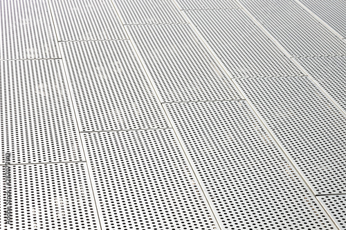 Diagonal view of metall grilles and round holes in metal surface, perforated panels