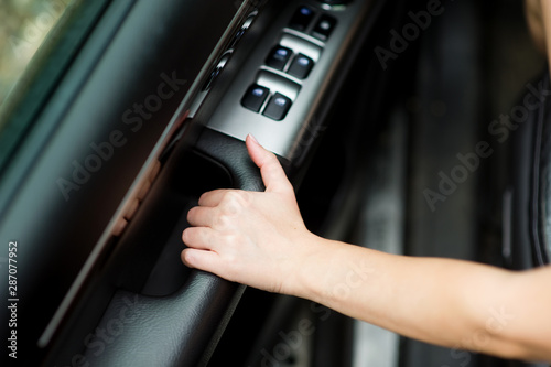 girl holds the inner door handle of a car, about to close it