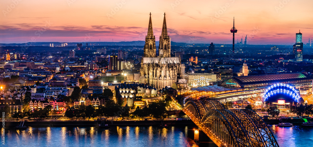 Beautiful night landscape of the gothic Cologne cathedral, Hohenzollern Bridge and the River Rhine at sunset and blue hour in Cologne, Germany
