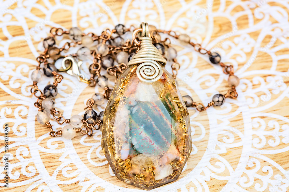 Orgonite pendant on mineral stone chain necklace placed on decorative background Orgonite pendant on mineral stone chain necklace placed on decorative background