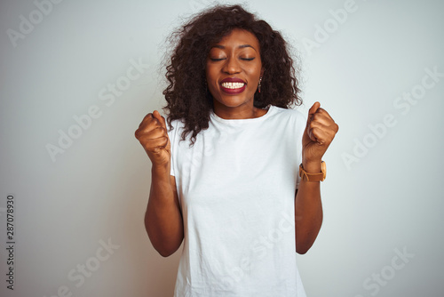 Young african american woman wearing t-shirt standing over isolated white background excited for success with arms raised and eyes closed celebrating victory smiling. Winner concept.