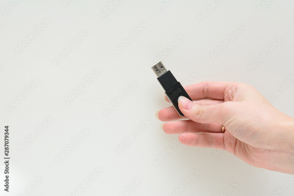 In a female hand a flash drive on a white background. Concept - electronic key In a female hand a flash drive on a white background. Concept - electronic key