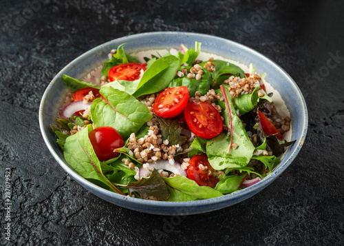 Buckwheat salad with cherry tomatoes, red onion and green vegetables. Healthy diet food
