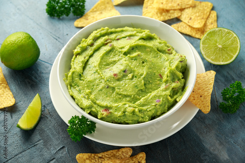 Bowl of fresh Guacamole with nachos chips and herbs. Healthy Vegan, Vegetables food. photo