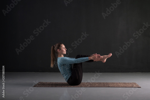 Fototapeta Naklejka Na Ścianę i Meble -  Caucasian girl practices yoga,doing boat pose, Navasana, exercise for abs. Variation for beginner. Studio shot