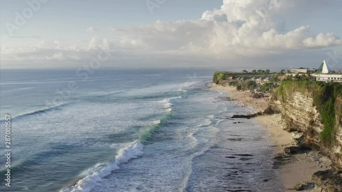 Flying above Dreamland beach, aerial view of the green and rocky coastline and blue ocean with foamy waves. Bali island, Indnesia photo