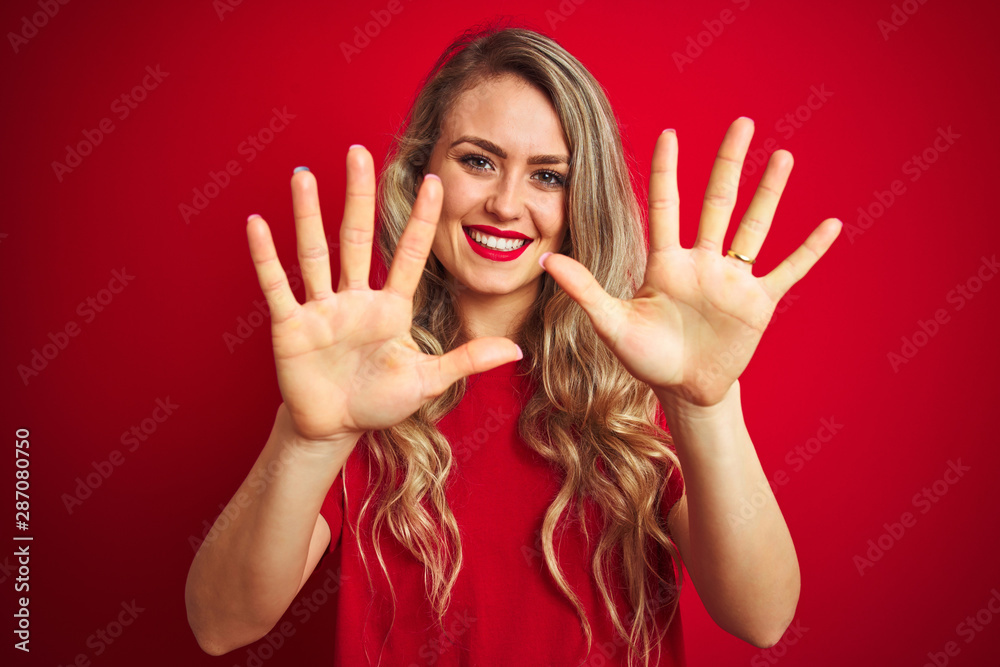 Young beautiful woman wearing basic t-shirt standing over red isolated background showing and pointing up with fingers number ten while smiling confident and happy. Young beautiful woman wearing basic t-shirt standing over red isolated background showing and pointing up with fingers number ten while smiling confident and happy.