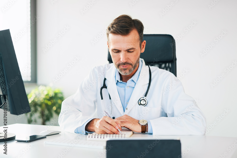 doctor sitting on office writing in calendar doctor sitting on office writing in calendar