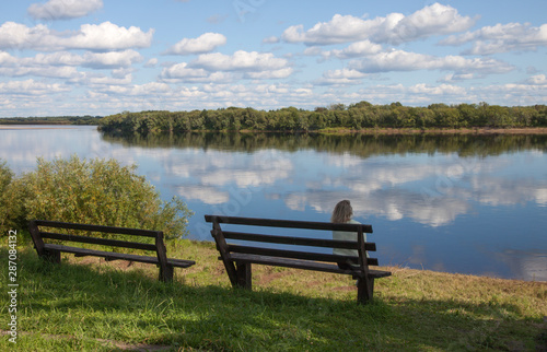 Beautiful landscape with river and clouds  and the girl on the bench © severga