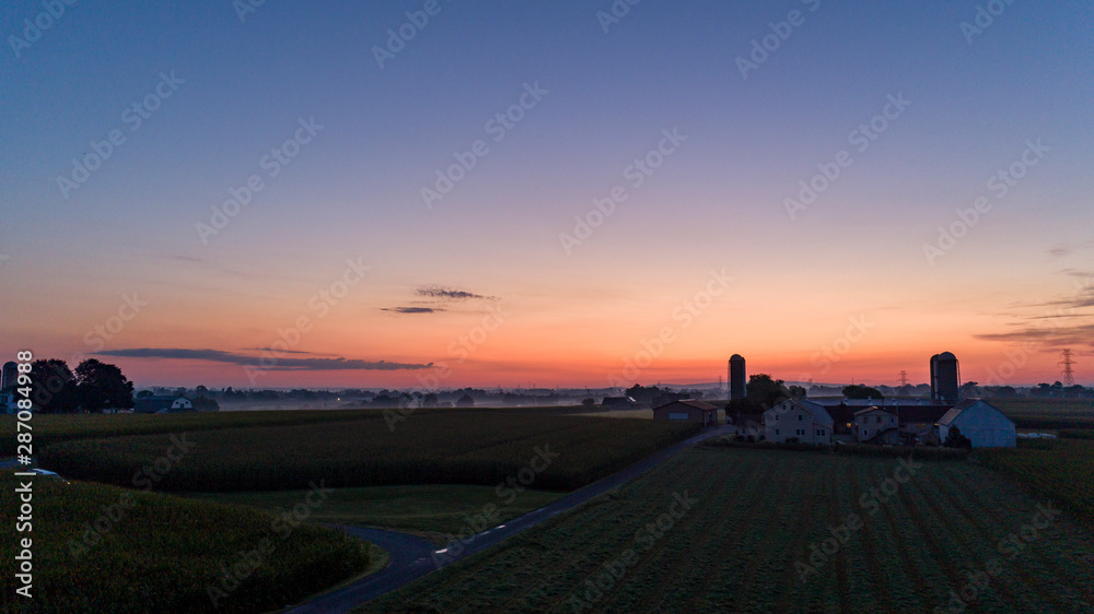 Obraz premium Sunrise Over an Amish Farm with Blues and Reds