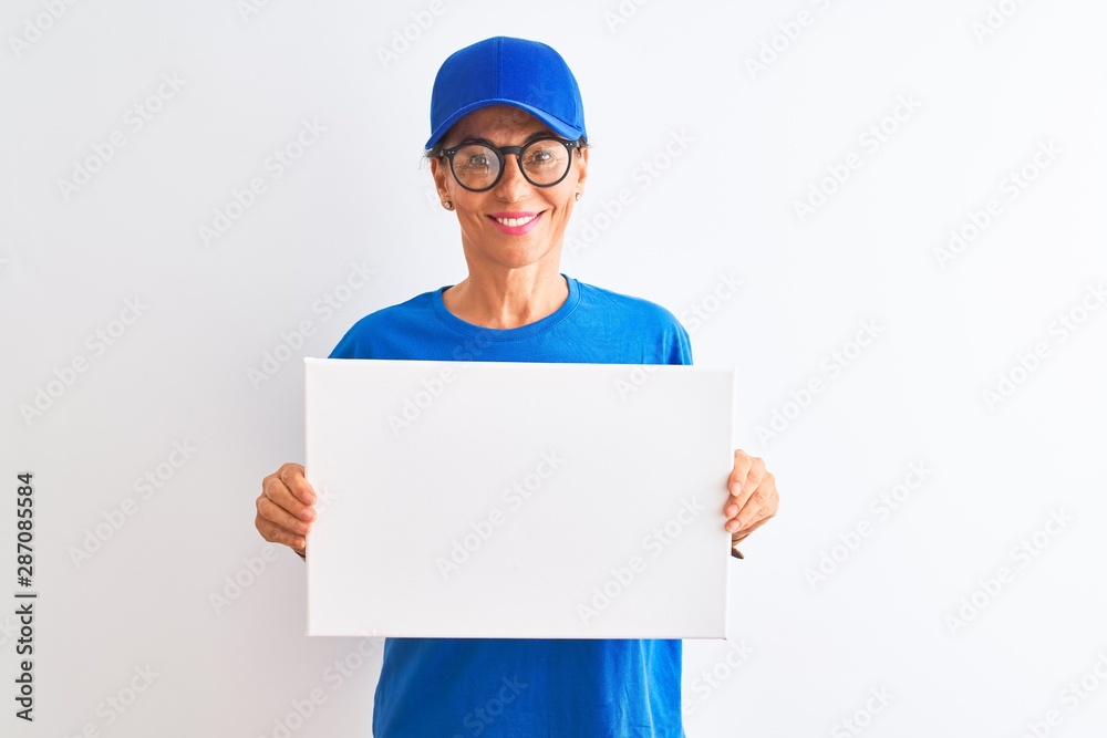 Senior deliverywoman wearing cap and glasses holding banner over isolated white background with a happy face standing and smiling with a confident smile showing teeth Senior deliverywoman wearing cap and glasses holding banner over isolated white background with a happy face standing and smiling with a confident smile showing teeth