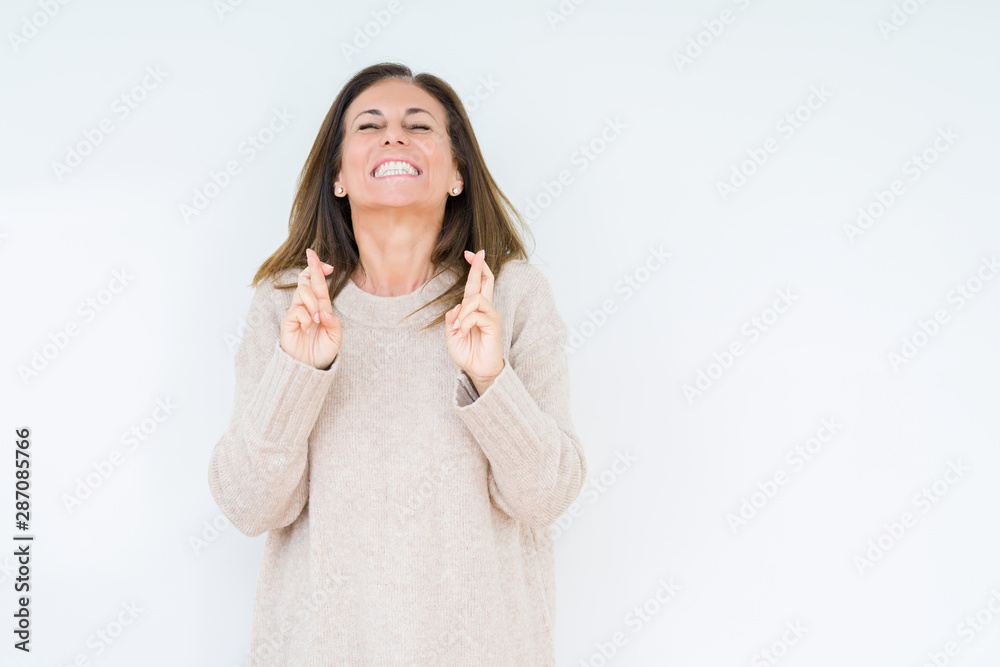 Beautiful middle age woman over isolated background smiling crossing fingers with hope and eyes closed. Luck and superstitious concept. Beautiful middle age woman over isolated background smiling crossing fingers with hope and eyes closed. Luck and superstitious concept.