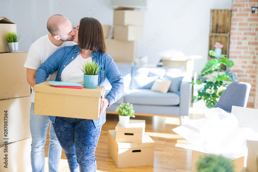Young couple moving to a new home, smiling happy holding cardboard boxes Young couple moving to a new home, smiling happy holding cardboard boxes