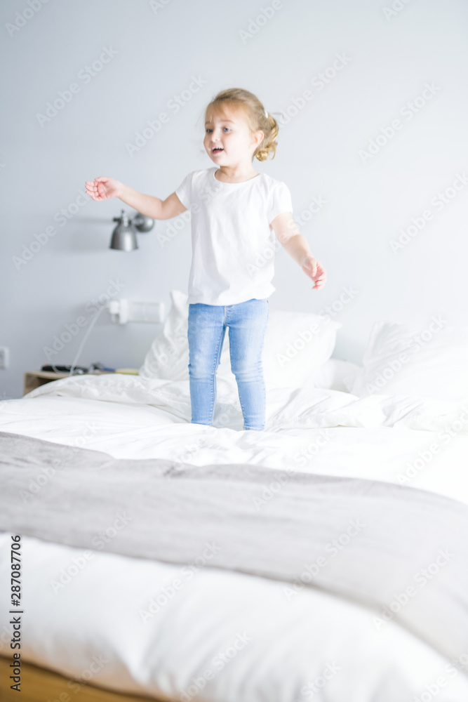 Fototapeta premium Beautiful. toddler child girl jumping on the bed