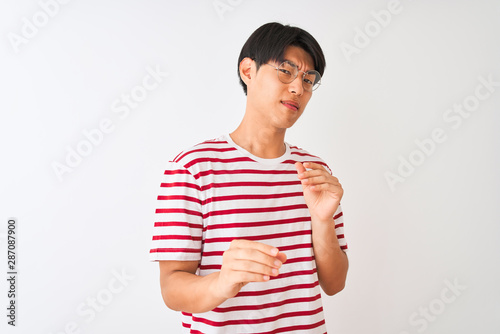 Young chinese man wearing glasses and striped t-shirt standing over isolated white background disgusted expression, displeased and fearful doing disgust face because aversion reaction.
