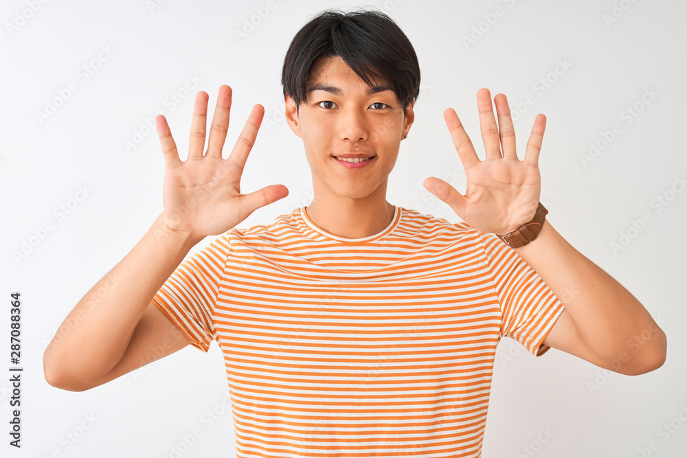 Young chinese man wearing casual striped t-shirt standing over isolated white background showing and pointing up with fingers number ten while smiling confident and happy. Young chinese man wearing casual striped t-shirt standing over isolated white background showing and pointing up with fingers number ten while smiling confident and happy.