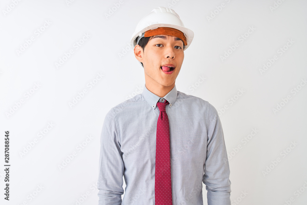 Chinese architect man wearing tie and helmet standing over isolated white background sticking tongue out happy with funny expression. Emotion concept. Chinese architect man wearing tie and helmet standing over isolated white background sticking tongue out happy with funny expression. Emotion concept.