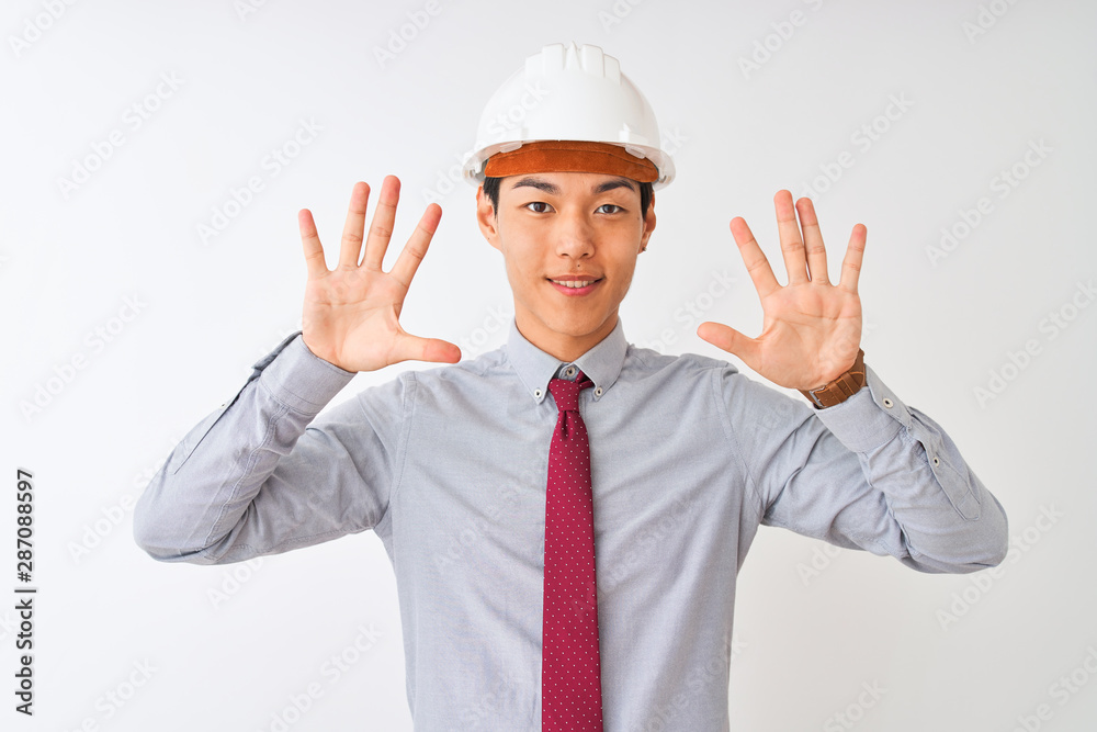 Chinese architect man wearing tie and helmet standing over isolated white background showing and pointing up with fingers number ten while smiling confident and happy. Chinese architect man wearing tie and helmet standing over isolated white background showing and pointing up with fingers number ten while smiling confident and happy.