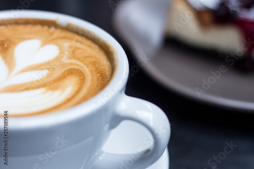 hot cafe latte  on table. blueberry cheesecake on background.