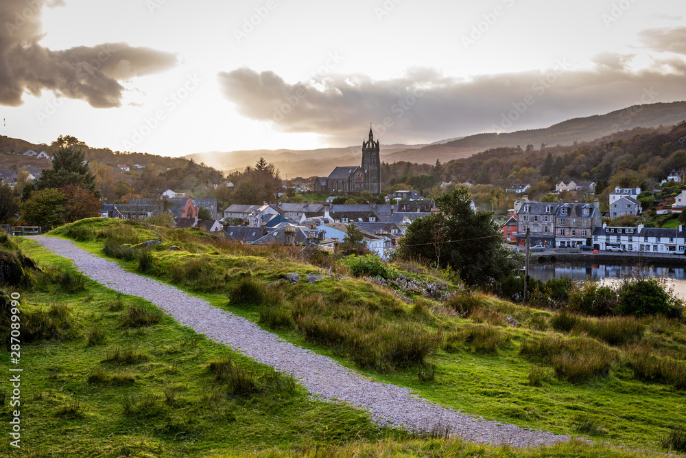 A path leads from right to left diagonally with the town of Tarbert leading to the horizon in Argyll and Bute Scotland United Kingdom