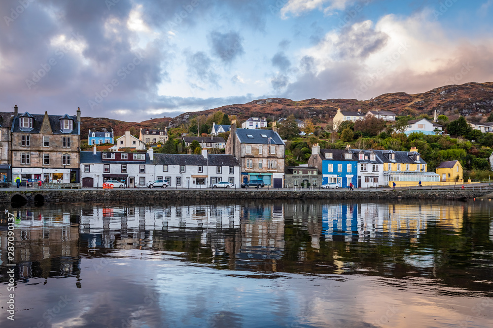 Still water of Tarbert Harbour reflect the beautifully painted houses on Barmore Rd in Argyll and Bute Scotland United Kingdom