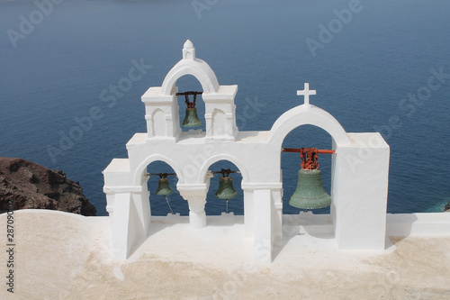 White church bells in Oia, Santorini with the sea in the background