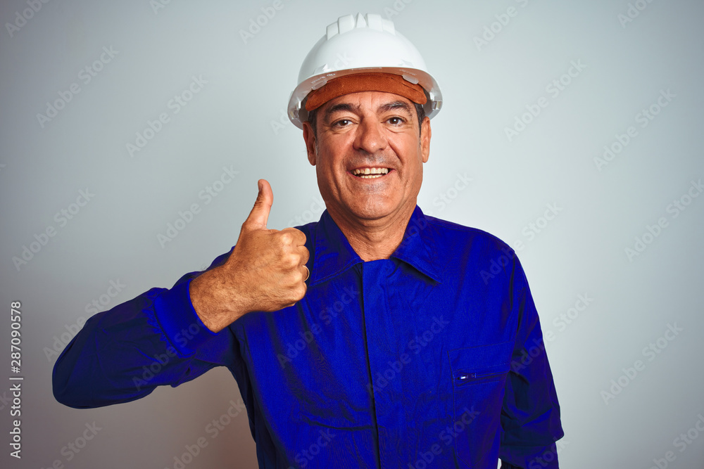 Handsome middle age worker man wearing uniform and helmet over isolated white background doing happy thumbs up gesture with hand. Approving expression looking at the camera showing success. Handsome middle age worker man wearing uniform and helmet over isolated white background doing happy thumbs up gesture with hand. Approving expression looking at the camera showing success.