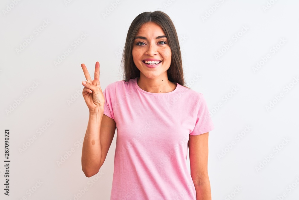 Young beautiful woman wearing pink casual t-shirt standing over isolated white background showing and pointing up with fingers number two while smiling confident and happy. Young beautiful woman wearing pink casual t-shirt standing over isolated white background showing and pointing up with fingers number two while smiling confident and happy.