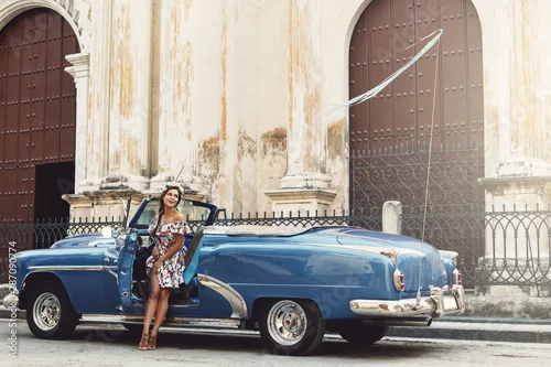Obraz Kobieta ubrana w piękną sukienkę i samochód retro kabriolet