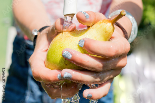 Little girl washes fresh pear under water photo