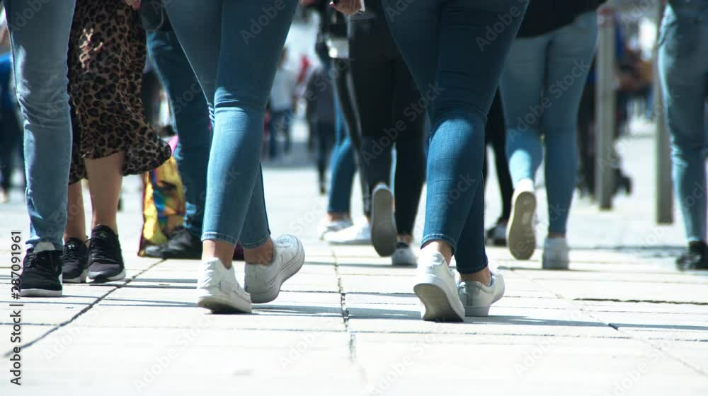 Relaxed girls in blue jeans are walking in the pedestrian area and shaking booty Relaxed girls in blue jeans are walking in the pedestrian area and shaking booty