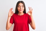 Young beautiful woman wearing red casual t-shirt standing over isolated white background relax and smiling with eyes closed doing meditation gesture with fingers. Yoga concept.