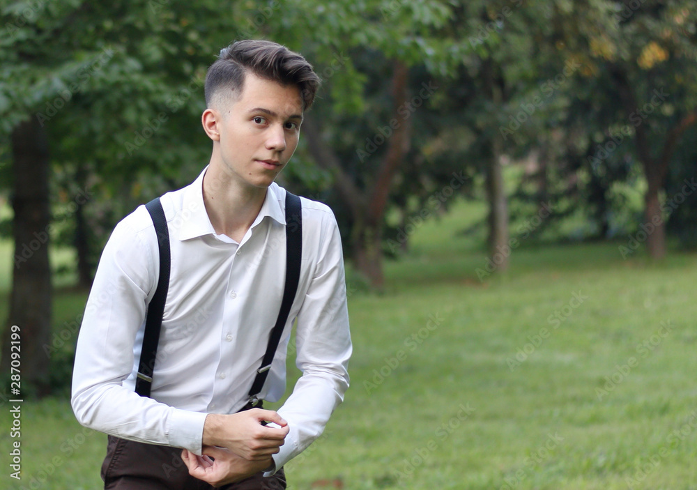 Stylishly dressed young man posing in a park. scaredly looking at the camera. Stylishly dressed young man posing in a park. scaredly looking at the camera.