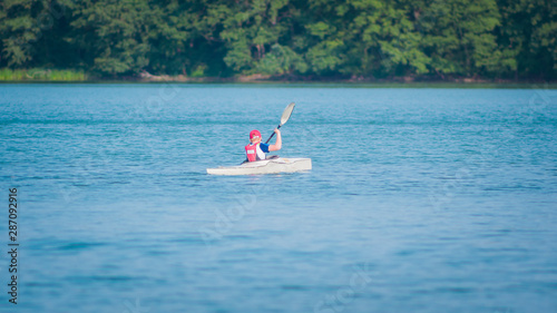 male athlete swims calmly in kayak waves in summer vacation on the lake sport fun machine