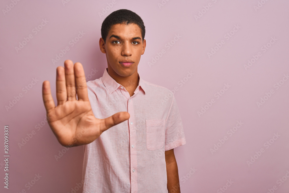 Young handsome arab man wearing casual shirt standing over isolated pink background doing stop sing with palm of the hand. Warning expression with negative and serious gesture on the face. Young handsome arab man wearing casual shirt standing over isolated pink background doing stop sing with palm of the hand. Warning expression with negative and serious gesture on the face.