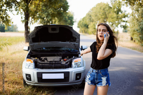 Angree girl call to the car service centre and asks for a help. Depressed student girl near broken car cries to the mobile phone.