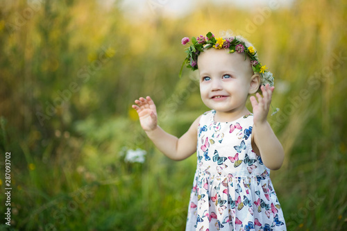 little girl with a wreath on her head and blue eyes smiles