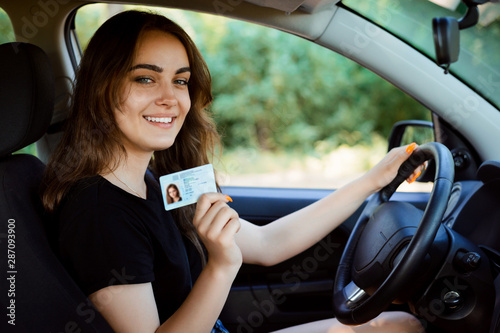 Student in a modern car showing driving licence