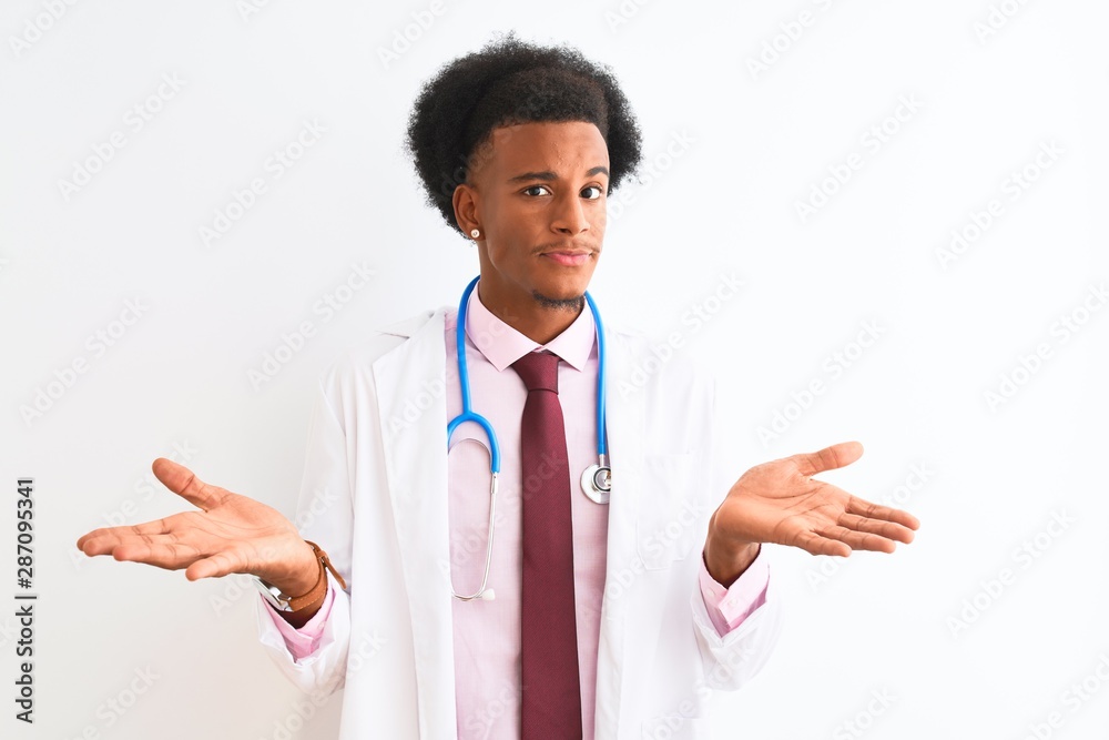 Young african american doctor man wearing sthetoscope over isolated white background clueless and confused expression with arms and hands raised. Doubt concept. Young african american doctor man wearing sthetoscope over isolated white background clueless and confused expression with arms and hands raised. Doubt concept.